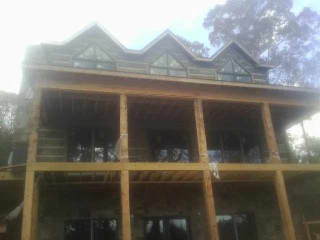 Dormers and porch framing on a large log home under construction — Roof Coating work by our crew in Churchville