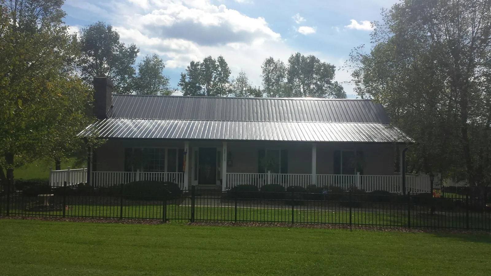 Gray metal roof on a brick ranch with a full width front porch — Gutter Guard Installation work by our crew in Churchville
