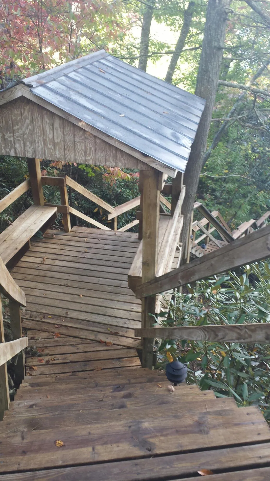 Metal roofed shelter over wooden steps on a wooded walkway — Skylight Repair & Installation work by our crew in Churchville