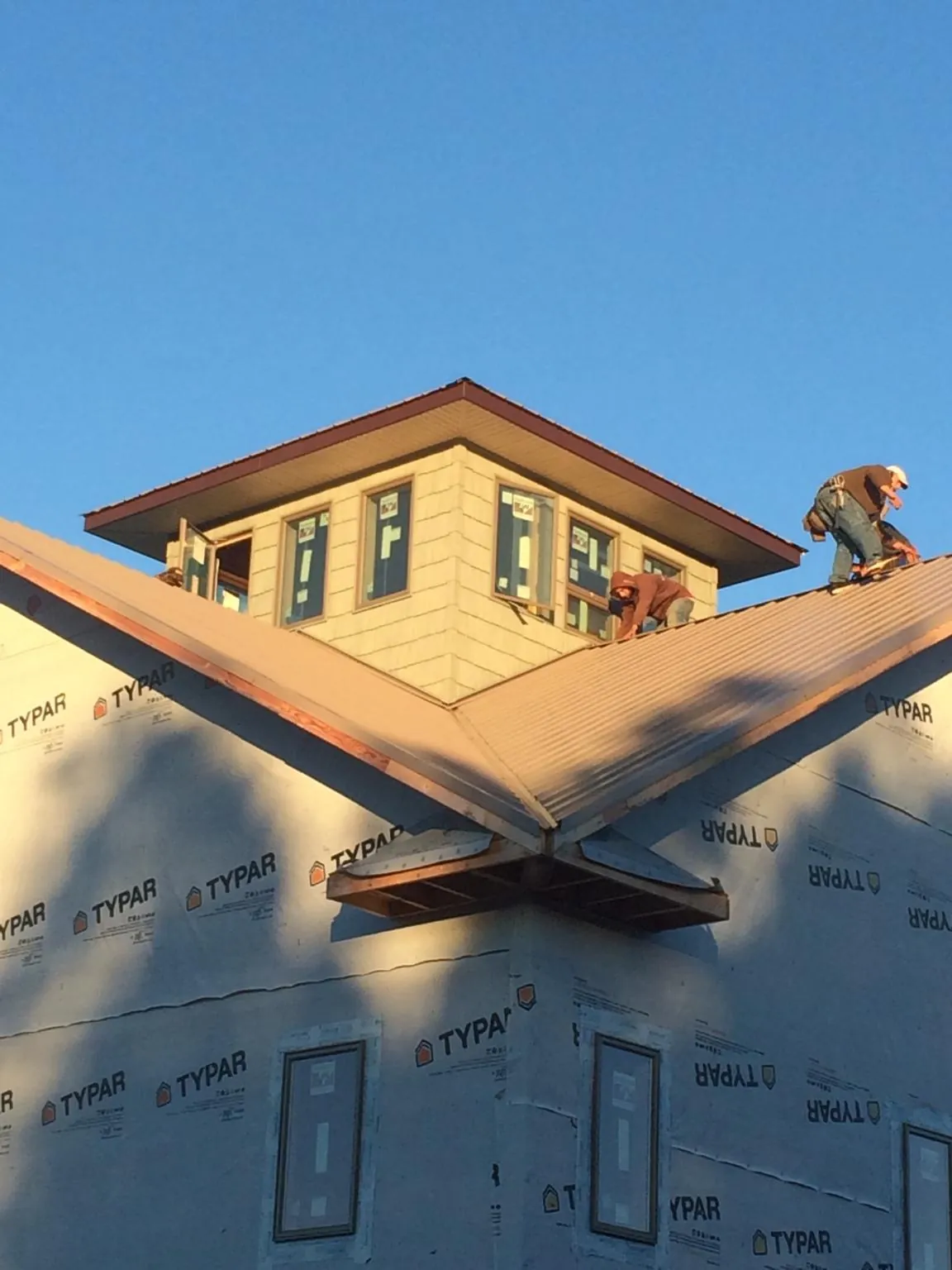 Roofers working around a rooftop cupola on a new metal roof at sunset — Roof Waterproofing in Churchville by Roofing Brothers